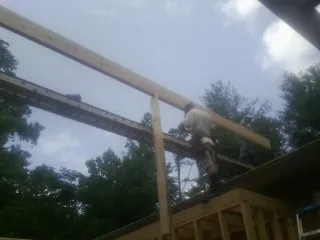 Carpenter setting a ridge beam over a new addition frame — Ice Dam Removal by Roofing Brothers in Redlands