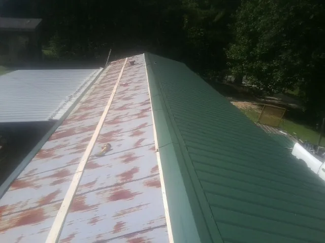Old rusted panels beside newly installed green metal roofing — Wind Damage Roof Repair by Roofing Brothers in Redlands
