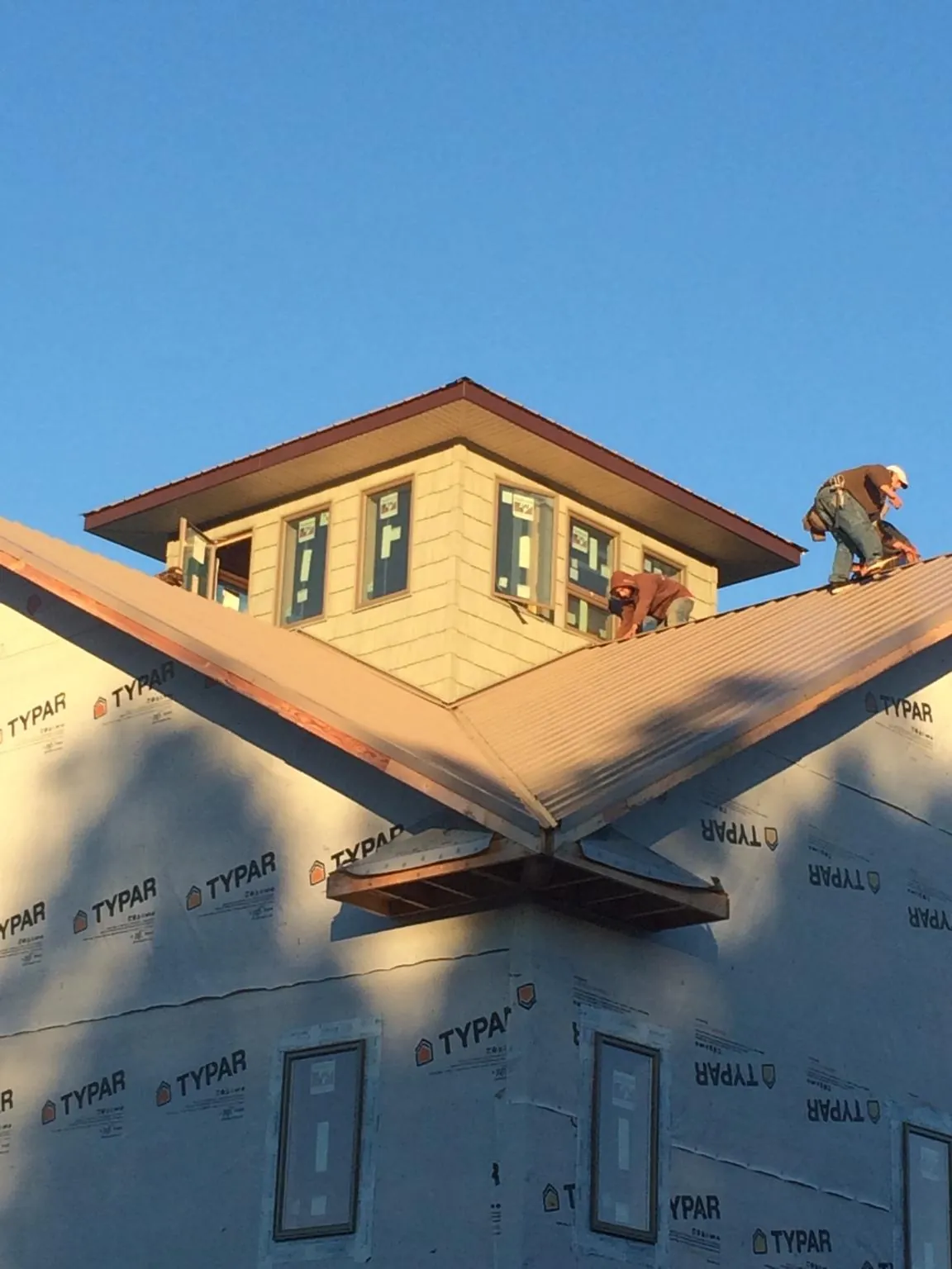 Roofers working around a rooftop cupola on a new metal roof at sunset — Roof Waterproofing in Redlands by Roofing Brothers